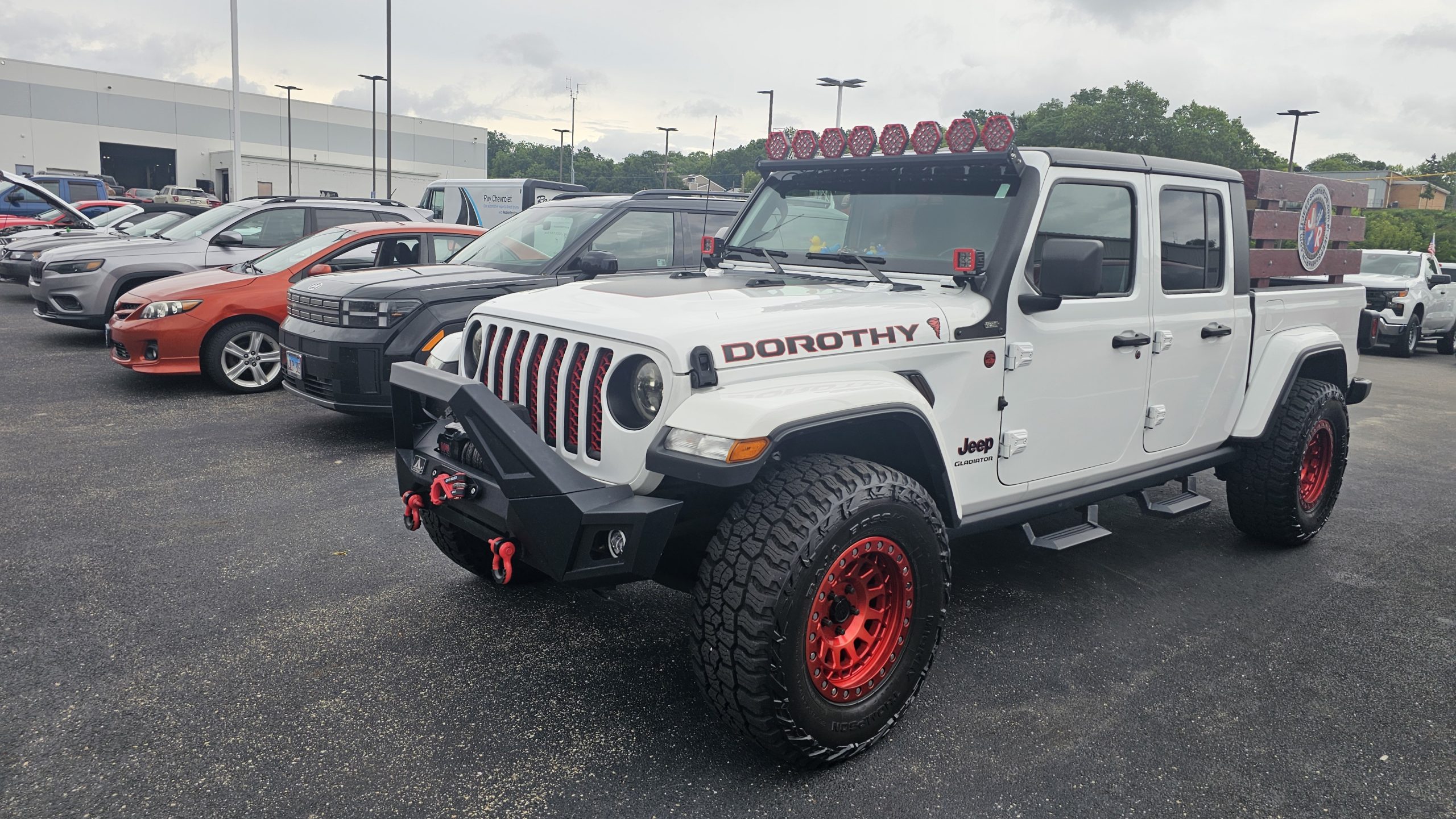 lineup of Jeep and Chevrolet cars at a dealership event