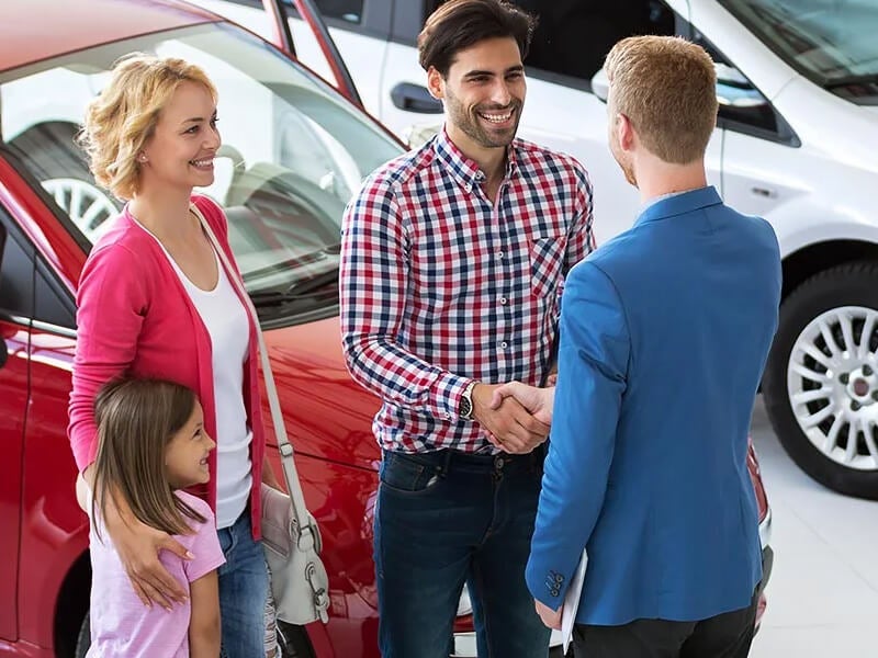 A family at a dealership talking to a sales rep